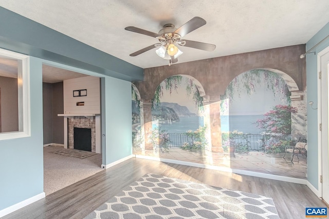 unfurnished living room with wood-type flooring, ceiling fan, and a textured ceiling