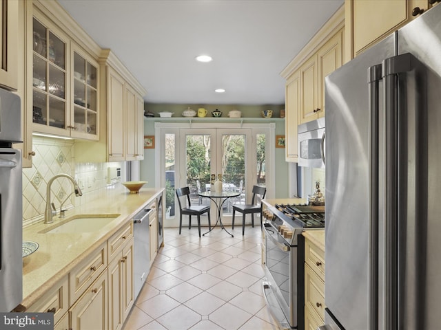 kitchen featuring appliances with stainless steel finishes, tasteful backsplash, sink, light tile patterned floors, and cream cabinets