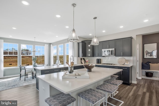 kitchen featuring hanging light fixtures, dark hardwood / wood-style floors, stainless steel appliances, and a kitchen breakfast bar