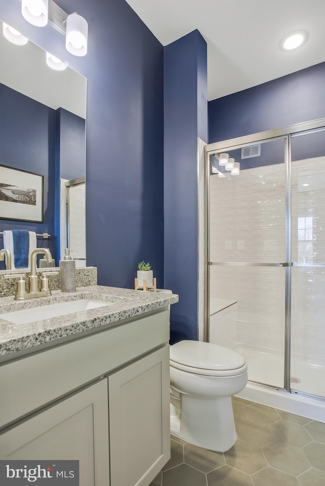 bathroom featuring vanity, a shower with door, tile patterned floors, and toilet