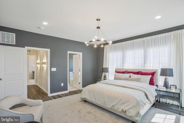 bedroom with hardwood / wood-style flooring, a notable chandelier, and ensuite bath