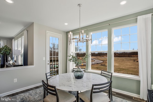 dining space with plenty of natural light, dark hardwood / wood-style floors, and a notable chandelier