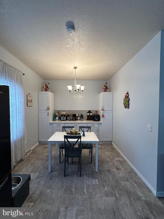 dining room with dark hardwood / wood-style flooring, a textured ceiling, and a chandelier