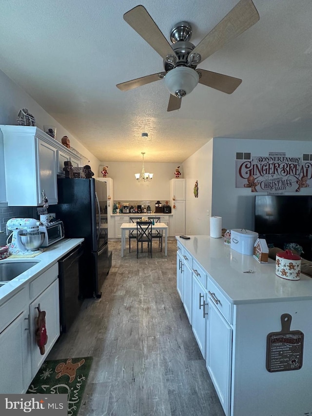 kitchen with white cabinetry, wood-type flooring, hanging light fixtures, a textured ceiling, and black dishwasher