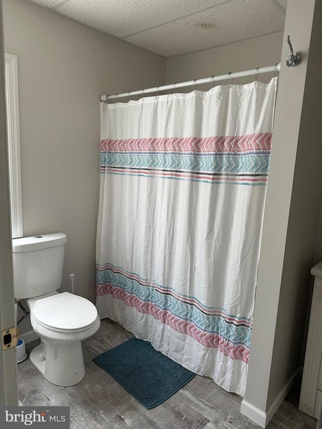 bathroom featuring a shower with curtain, a paneled ceiling, and toilet