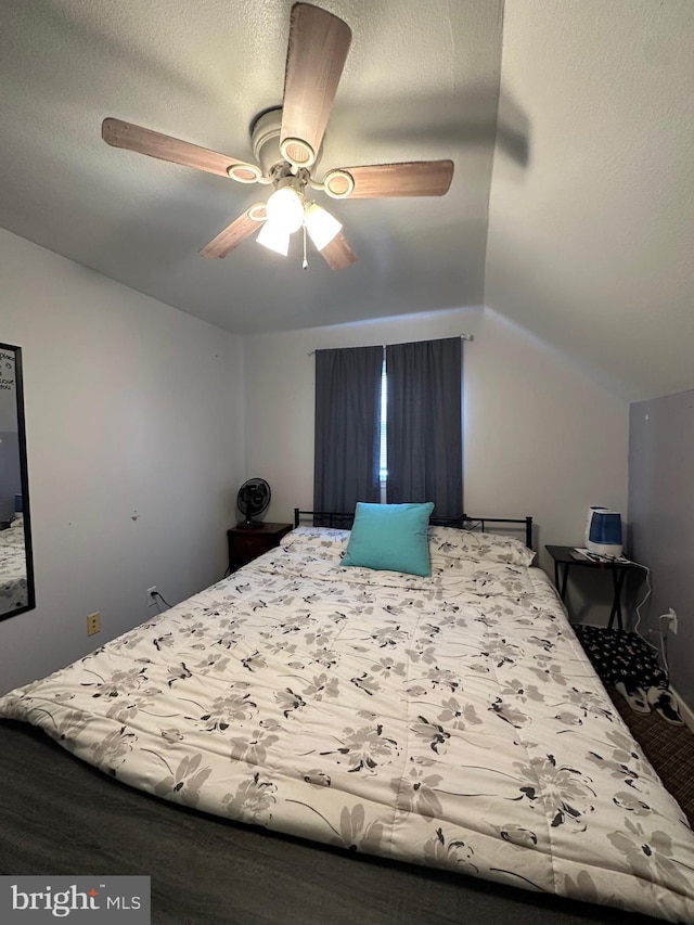 bedroom with lofted ceiling, a textured ceiling, and ceiling fan