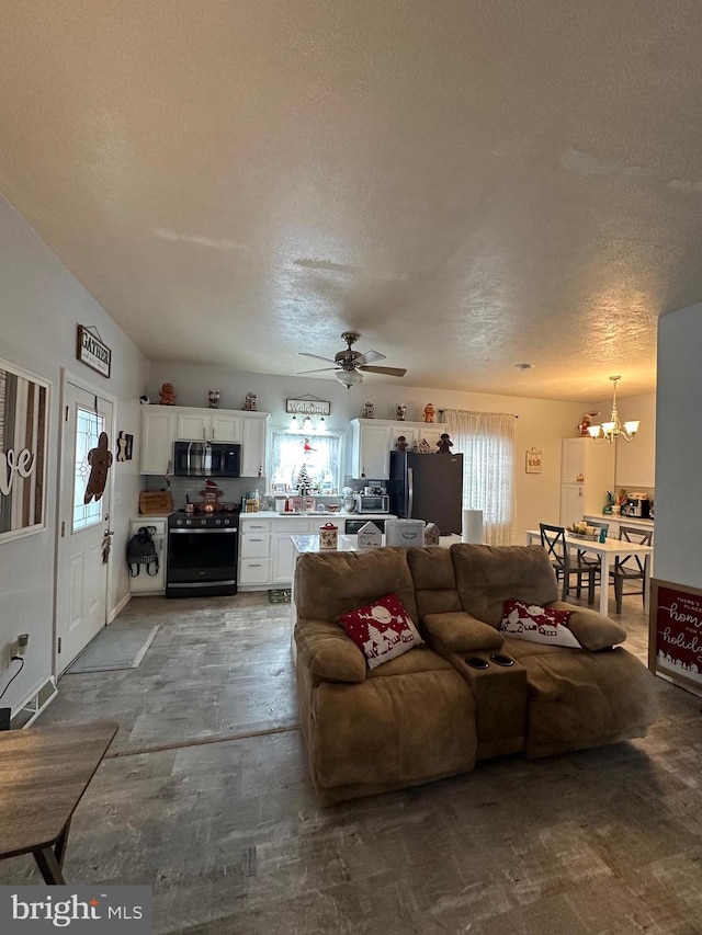 living room featuring lofted ceiling, a healthy amount of sunlight, ceiling fan with notable chandelier, and a textured ceiling