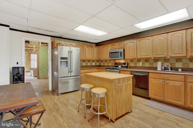 kitchen featuring a breakfast bar, sink, a center island, light hardwood / wood-style flooring, and appliances with stainless steel finishes