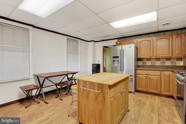 kitchen featuring range, a drop ceiling, light wood-type flooring, high quality fridge, and backsplash