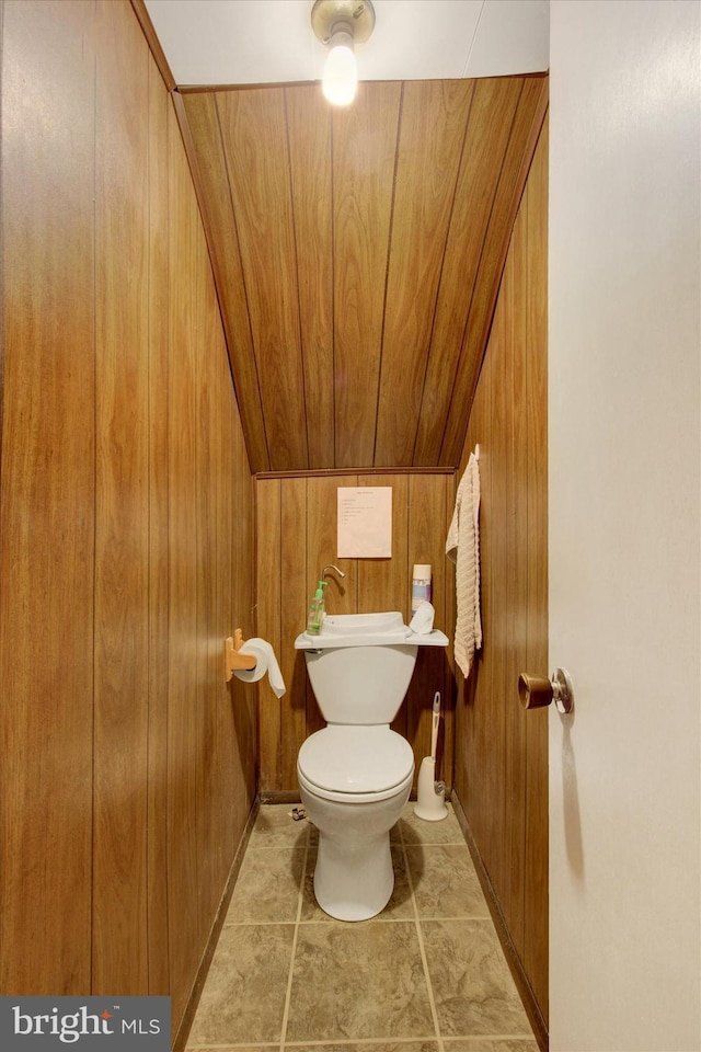 bathroom with toilet and wood walls