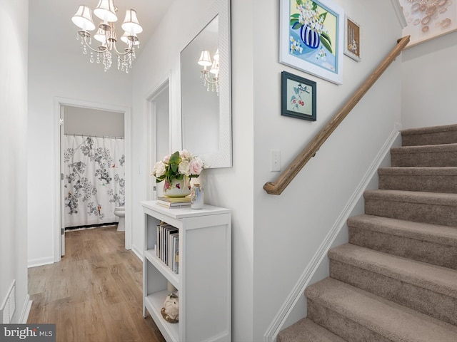 stairway with wood-type flooring and a chandelier