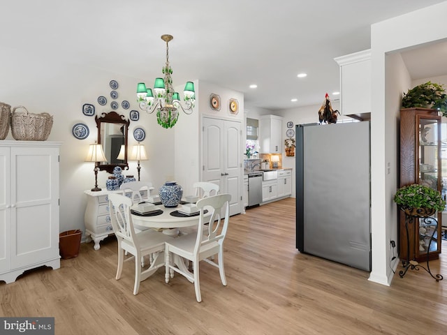 dining space with an inviting chandelier and light hardwood / wood-style flooring