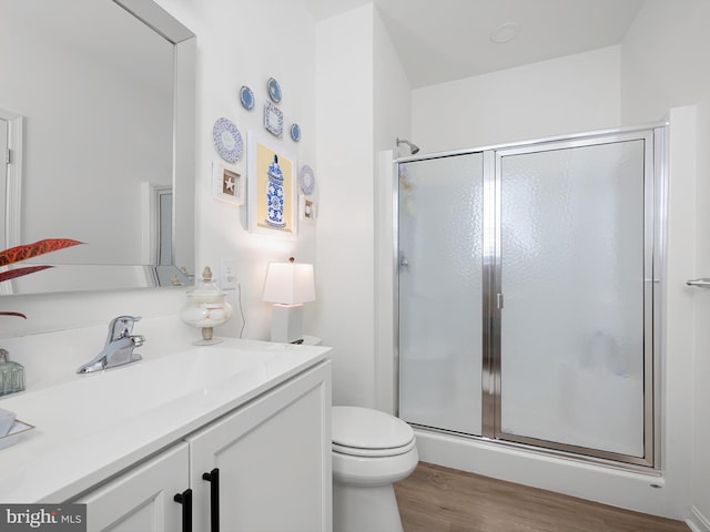 bathroom featuring vanity, hardwood / wood-style floors, a shower with shower door, and toilet