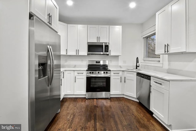 kitchen with sink, dark wood-type flooring, appliances with stainless steel finishes, white cabinetry, and light stone counters