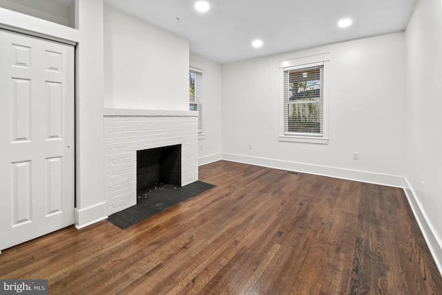 unfurnished living room featuring dark wood-type flooring and a fireplace