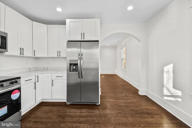 kitchen with white cabinetry, appliances with stainless steel finishes, dark hardwood / wood-style floors, and light stone counters