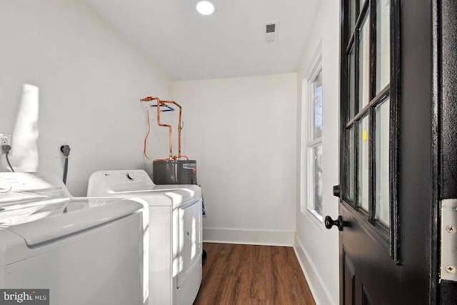 washroom featuring dark wood-type flooring, washer and clothes dryer, water heater, and a wealth of natural light