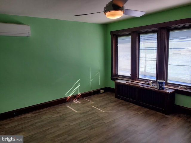 empty room with dark wood-type flooring, ceiling fan, a wall unit AC, and a wealth of natural light