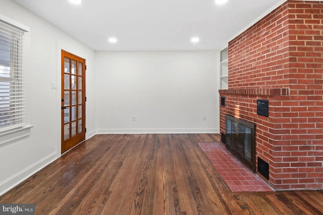 unfurnished living room featuring built in shelves, a fireplace, and dark hardwood / wood-style floors