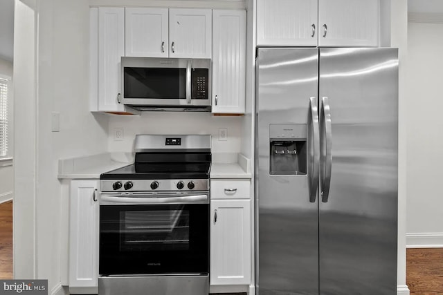 kitchen with white cabinetry, stainless steel appliances, and hardwood / wood-style floors