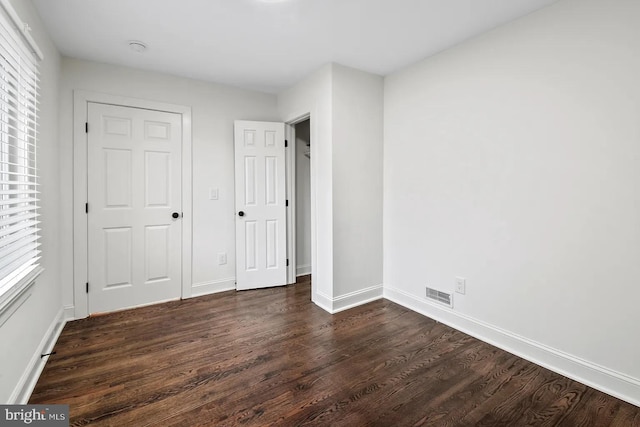 unfurnished bedroom featuring dark hardwood / wood-style flooring and a closet