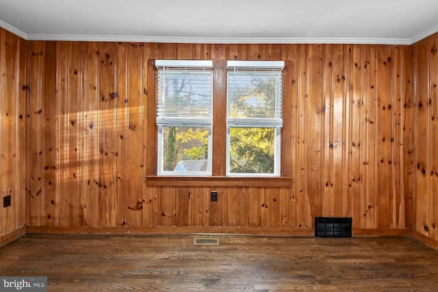 spare room with ornamental molding, dark wood-type flooring, and wood walls