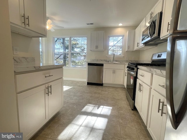 kitchen featuring ceiling fan, stainless steel appliances, light tile patterned floors, and white cabinets