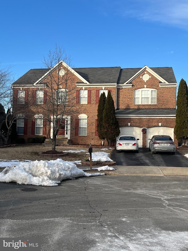 view of front of home featuring aphalt driveway, an attached garage, and brick siding