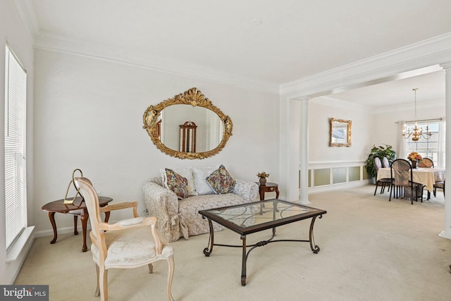 living area with a notable chandelier, decorative columns, crown molding, and carpet floors