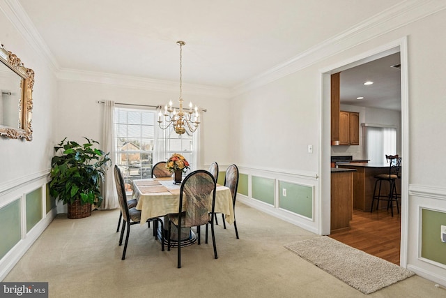 dining space featuring an inviting chandelier, crown molding, a decorative wall, and light carpet