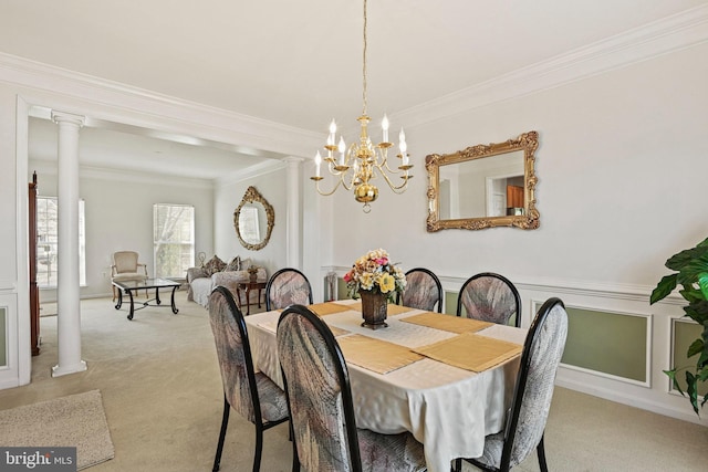 dining space with crown molding, a notable chandelier, light colored carpet, and ornate columns