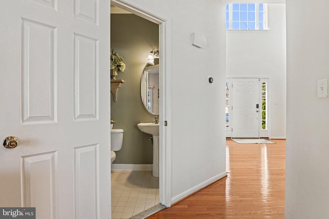 interior space with a sink, toilet, baseboards, and wood finished floors