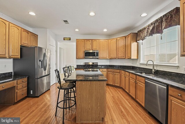 kitchen featuring visible vents, a sink, a kitchen breakfast bar, a kitchen island, and stainless steel appliances