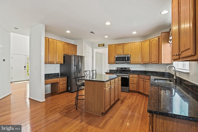 kitchen featuring visible vents, a kitchen island, appliances with stainless steel finishes, built in study area, and a sink