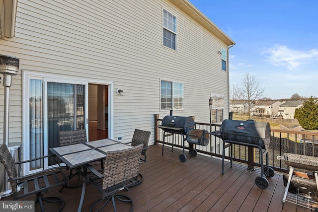 wooden terrace featuring outdoor dining space and area for grilling