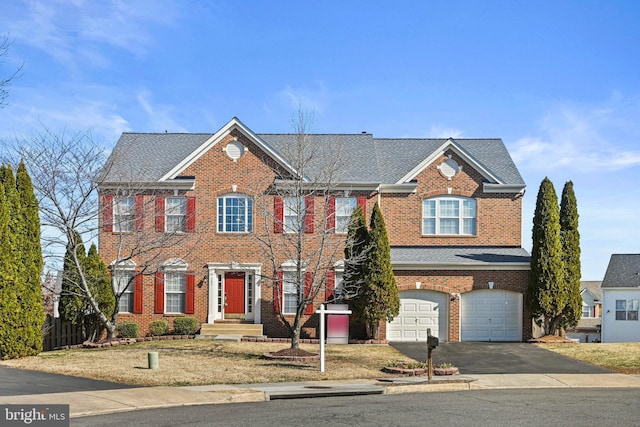 view of front facade with fence, an attached garage, a shingled roof, aphalt driveway, and brick siding