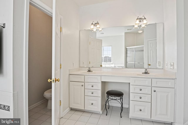 full bath with toilet, double vanity, a stall shower, tile patterned floors, and a sink