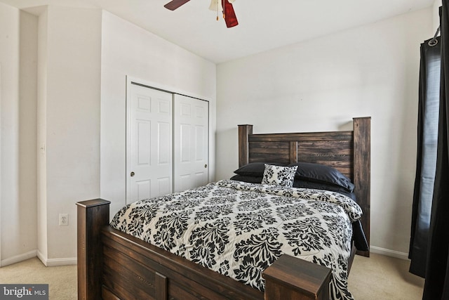 bedroom with a closet, light colored carpet, baseboards, and ceiling fan