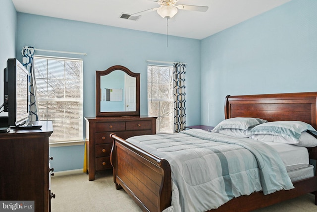 bedroom with light carpet, visible vents, multiple windows, and baseboards