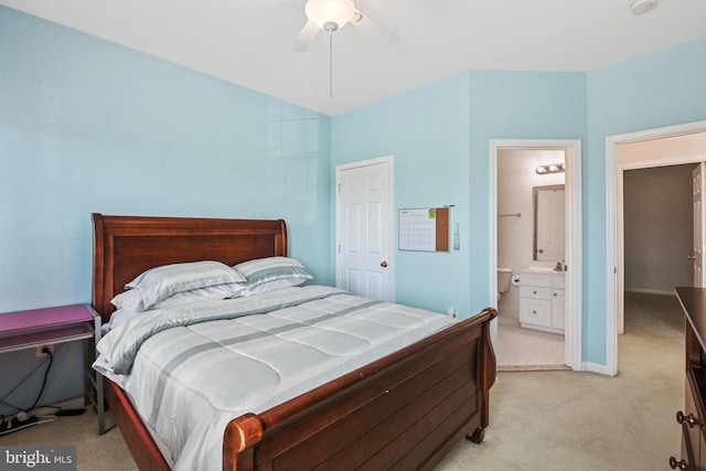 bedroom featuring light carpet, baseboards, ensuite bath, and a ceiling fan