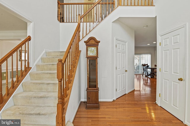 stairs with recessed lighting, baseboards, a high ceiling, and hardwood / wood-style flooring