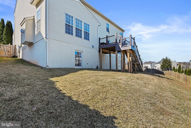 rear view of property featuring a lawn, a wooden deck, stairs, and fence