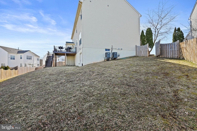 rear view of house featuring a yard, stairway, and a fenced backyard