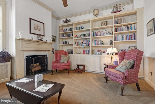 living area with ceiling fan, built in features, ornamental molding, and light carpet