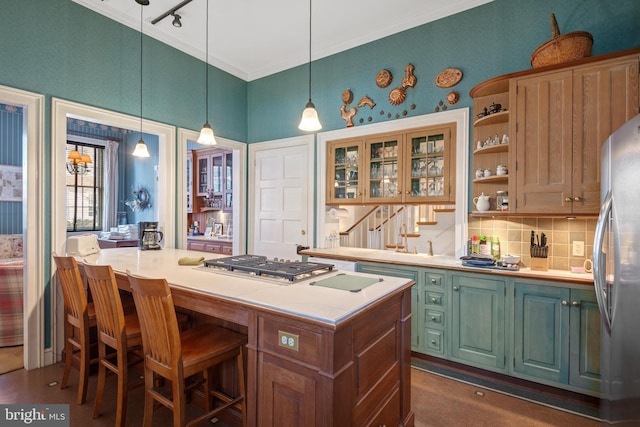 kitchen with pendant lighting, stainless steel appliances, a kitchen breakfast bar, ornamental molding, and a kitchen island