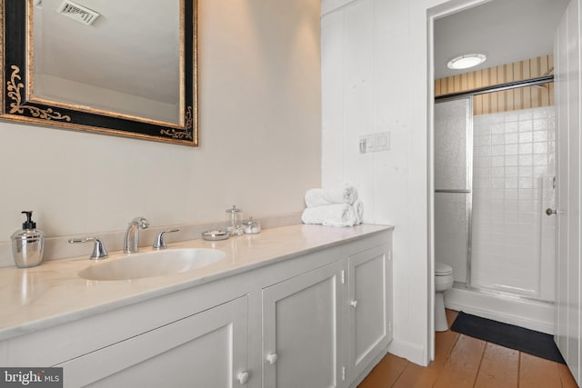 bathroom with a shower with door, vanity, wood-type flooring, and toilet