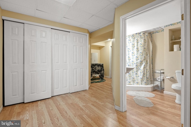 unfurnished bedroom with hardwood / wood-style flooring, a paneled ceiling, and a closet