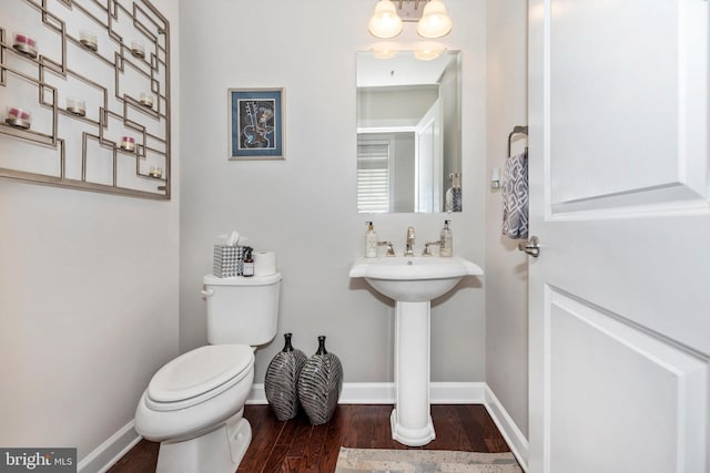 bathroom with hardwood / wood-style flooring, sink, an inviting chandelier, and toilet