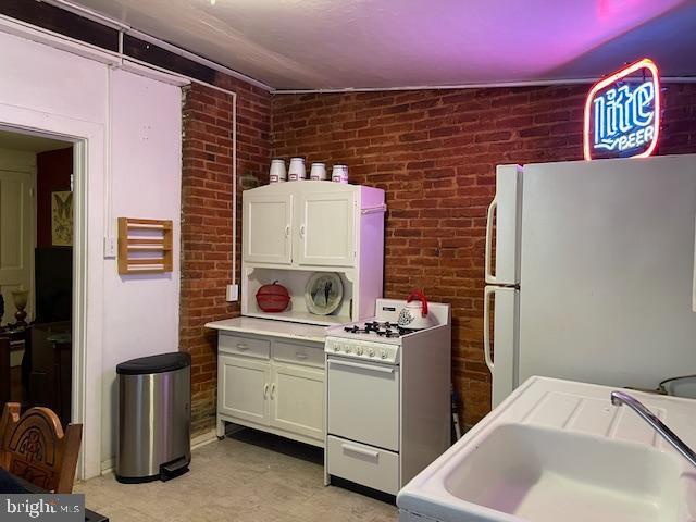 kitchen with lofted ceiling, sink, white appliances, and white cabinets