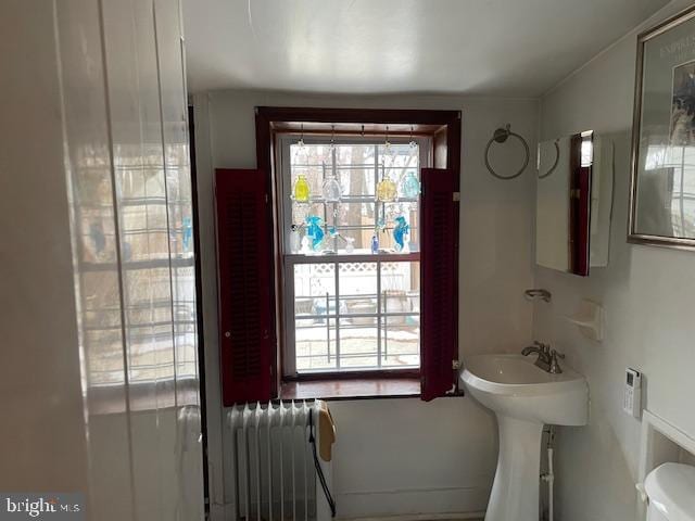 bathroom with radiator heating unit, toilet, and sink